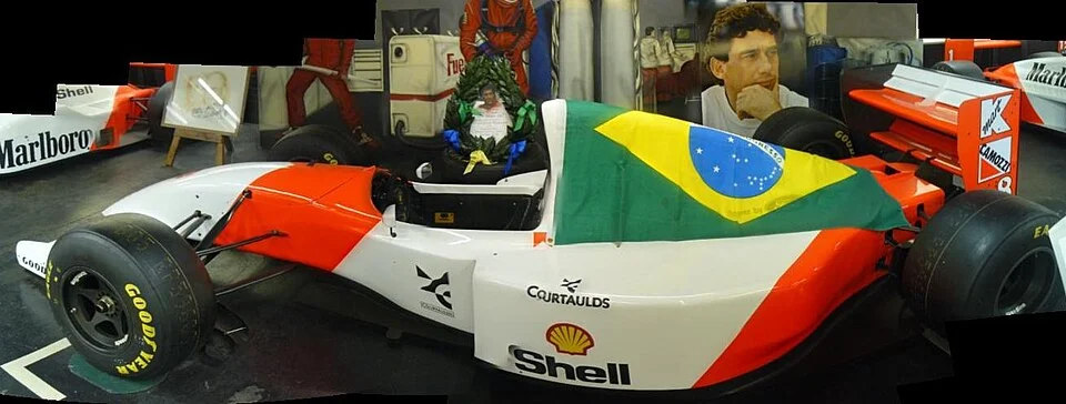 Κόκκινη και λευκή McLaren MP4/8 σε έκθεση, με βραζιλιάνικη σημαία πάνω της.