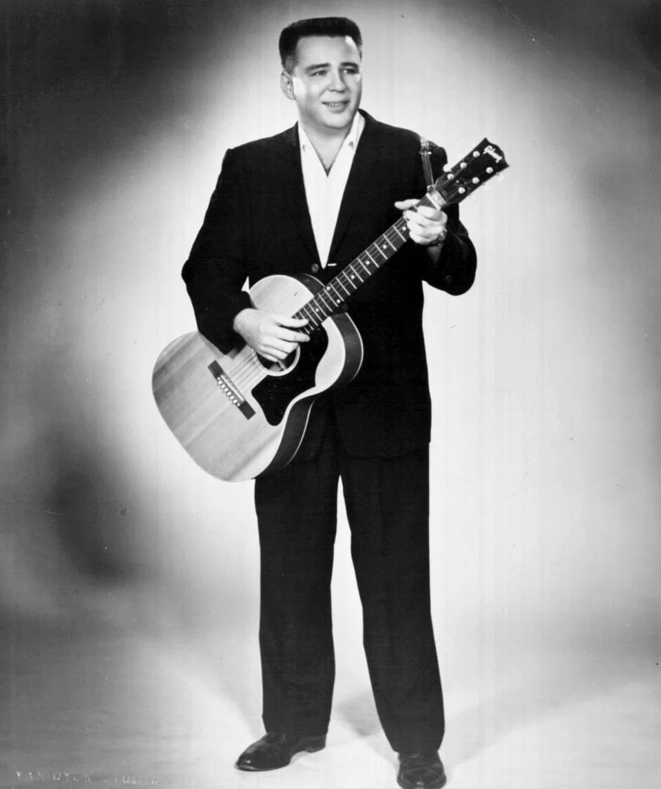 Ο J. P. Richardson, γνωστός ως The Big Bopper, σε ασπρόμαυρη φωτογραφία, κρατώντας κιθάρα