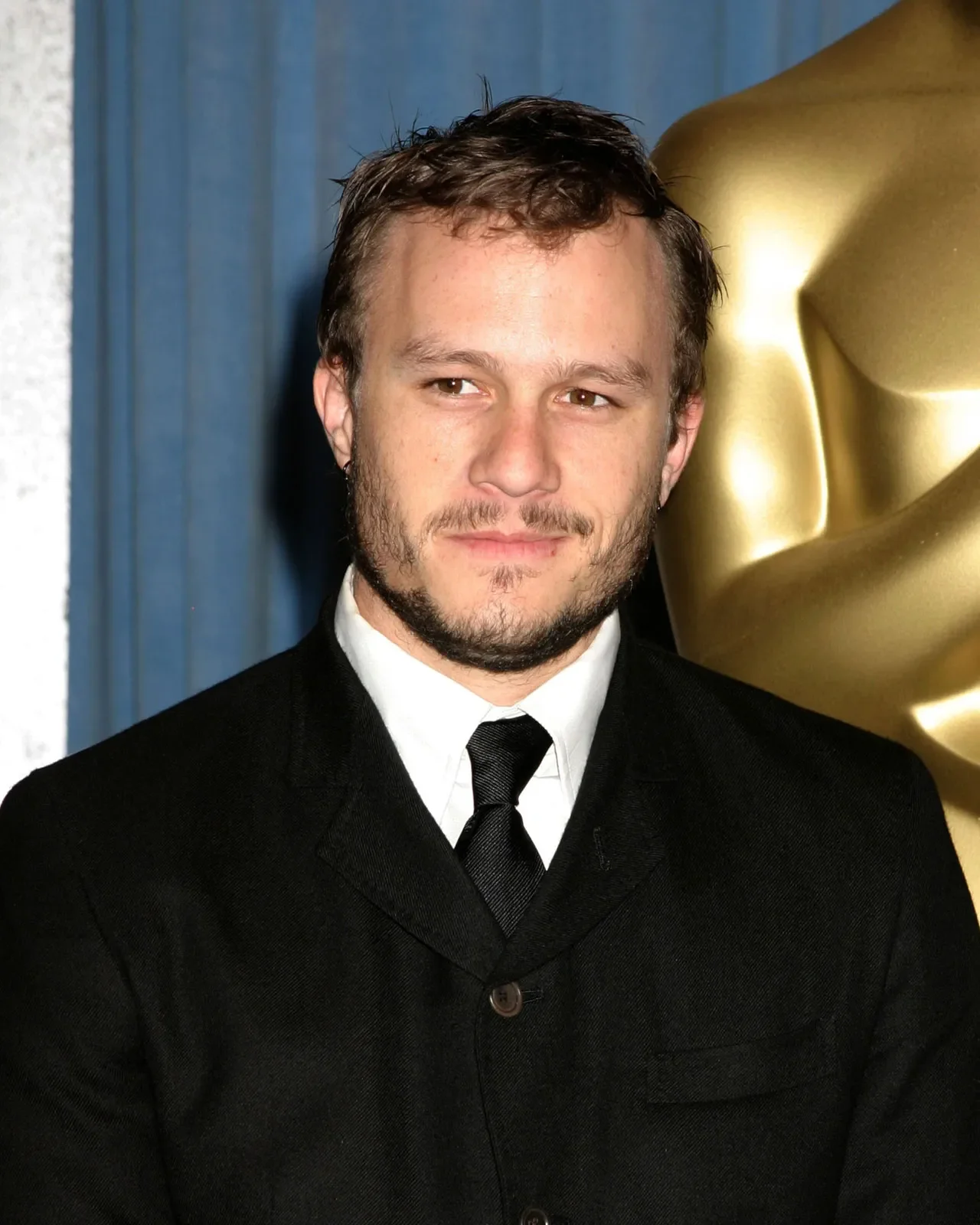 Ο Heath Ledger με σκούρο μπλε σακάκι, κοιτάζει κατάματα τον φακό