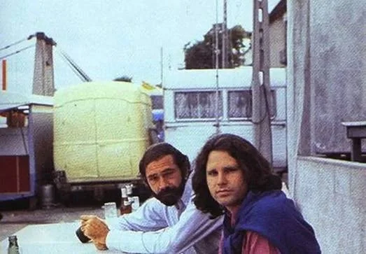 Ο Jim Morrison με μπλε πουλόβερ στους ώμους, δίπλα σε έναν άνδρα