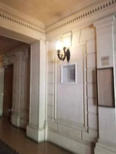 Κοινόχρηστος διάδρομος με λευκές διακοσμητικές επενδύσεις και φωτιστικό τοίχου