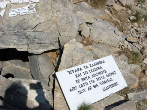 Λευκή πλάκα πάνω σε βράχους με την επιγραφή «Έγραψα τα Ελληνικά και το Γκέμμα σε εφτά χρόνους από οργή για τους αιώνες που δε θα υπάρχω. Λιαντίνης»