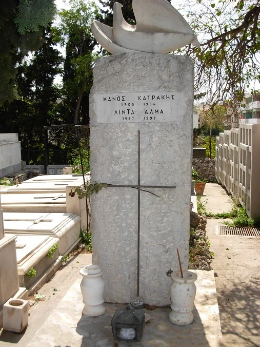 Το κοινό μνήμα του Μάνου Κατράκη και της Λίντας Άλμα, με όρθια μαρμάρινη στήλη, γλυπτό και λουλούδια.
