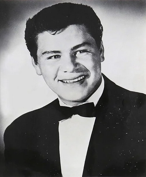 Ασπρόμαυρο πορτρέτο του Ritchie Valens με σακάκι, πουκάμισο και παπιγιόν