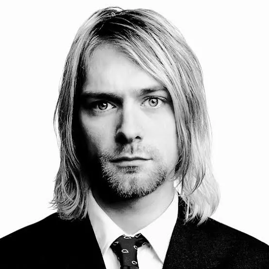 Ασπρόμαυρο πορτρέτο του Kurt Cobain σε λευκό φόντο. Φοράει σκούρο κοστούμι, λευκό πουκάμισο και μια σκούρα γραβάτα με μοτίβα. Τα μαλλιά του είναι ίσια και πέφτουν στους ώμους.
